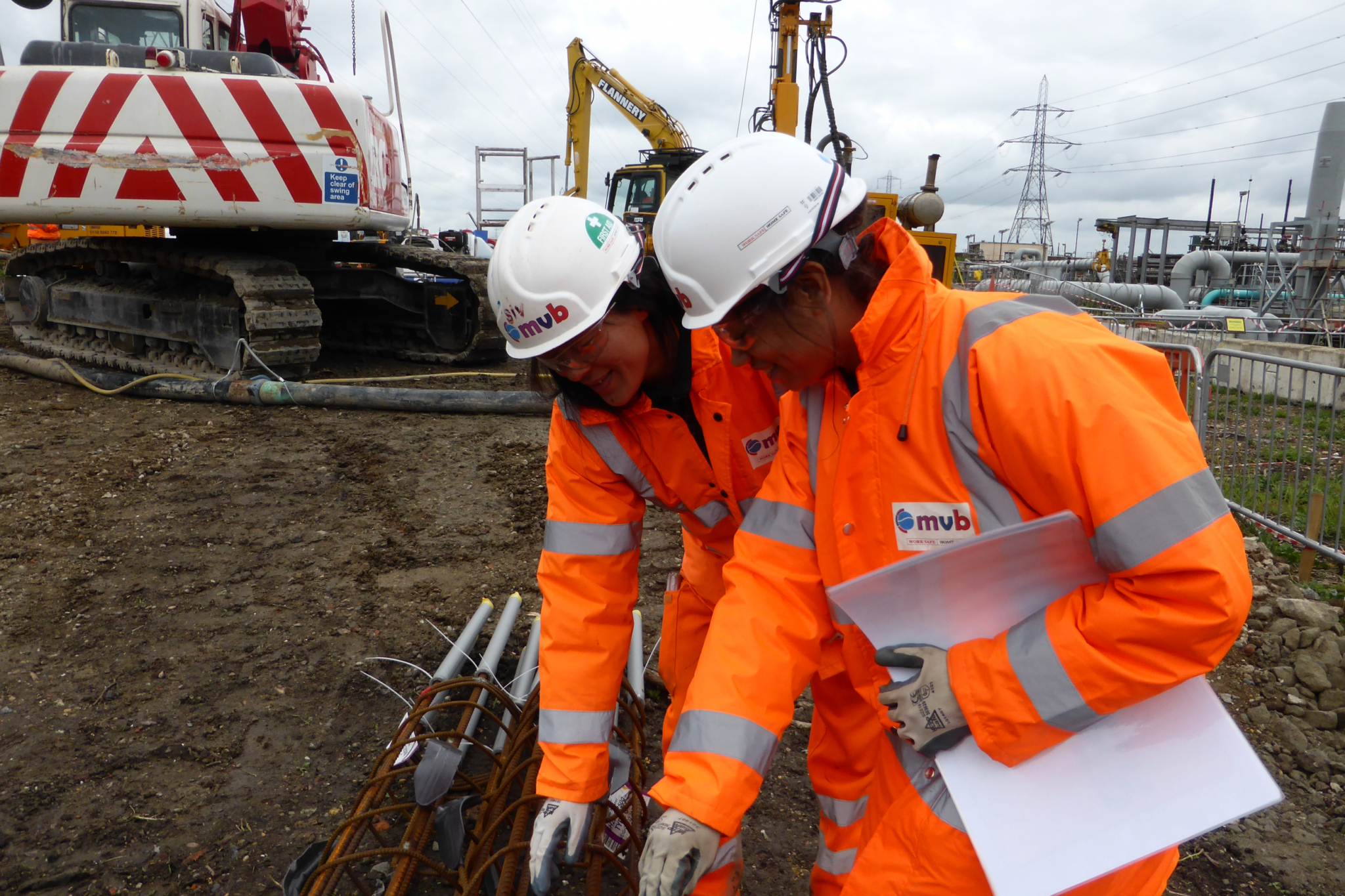 Sivilay Sayavong on site helping guide colleague in technical reinforcement detail in ppe